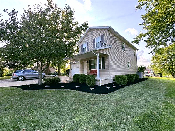 A house with a wide mulch bed along the side and a shade tree.