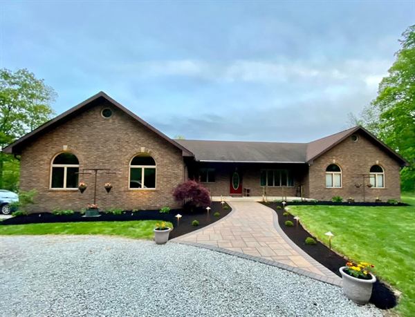 A brick ranch with a wide paver front walk bordered by fresh black mulch beds.