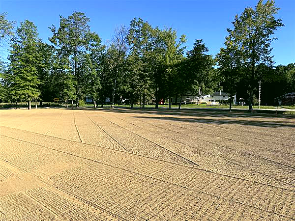 A large graded and seeded field beside a tree line, ready to grow in.