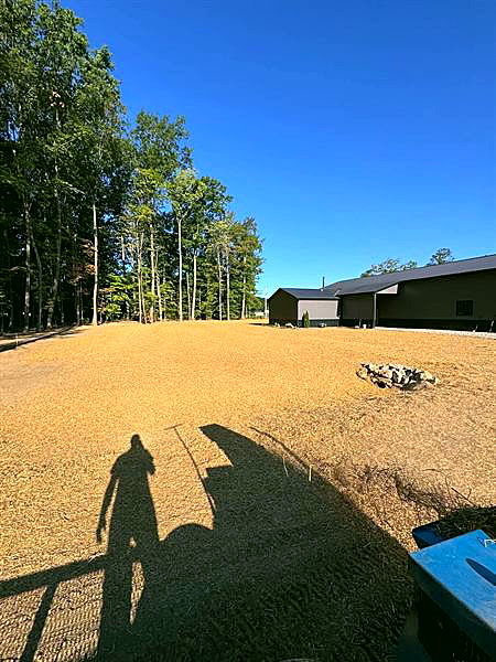 Freshly graded bare soil beside a pole barn, ready for seed.