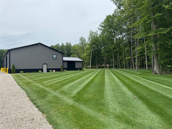 The same pole barn a season later with a thick, striped lawn.